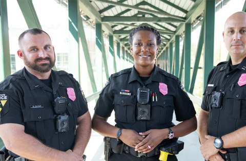 Three law enforcement officers wearing pink awareness badges.